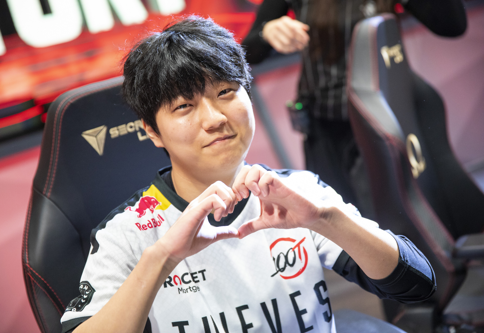 Ssumday competing on stage in the LCS, making a heart shape with his hands.