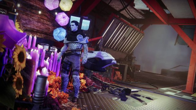 A man with blueish skin from Destiny 2 stands in a building surrounded by purple candles.