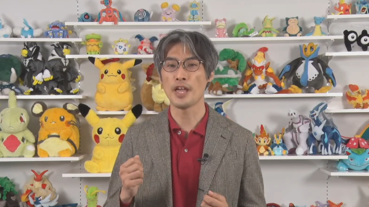 COO of The Pokemon Company talking in front of Pokémon plushies.