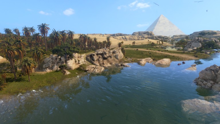 A blue expanse of water with lush greenery on one side, and a large pyramid looming the the skyline in the distance