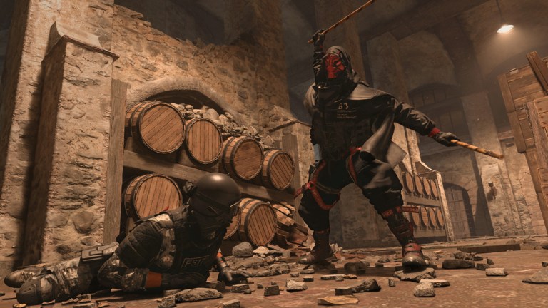 A character in military gear is beaten on the ground by another character wearing a red mask in a cellar on Vondel in DMZ.