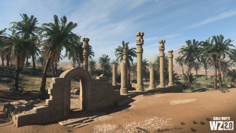 A group of ruined buildings and pillars in the desert, with palm trees and an oasis in the background on Al Mazrah in DMZ.