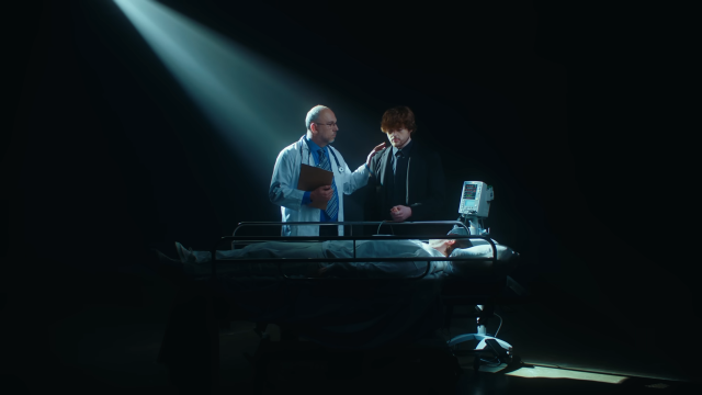 Technodad with his hand on Dream's shoulder as they stand over an actor playing Technoblade in the Unil I End Up Dead music video.