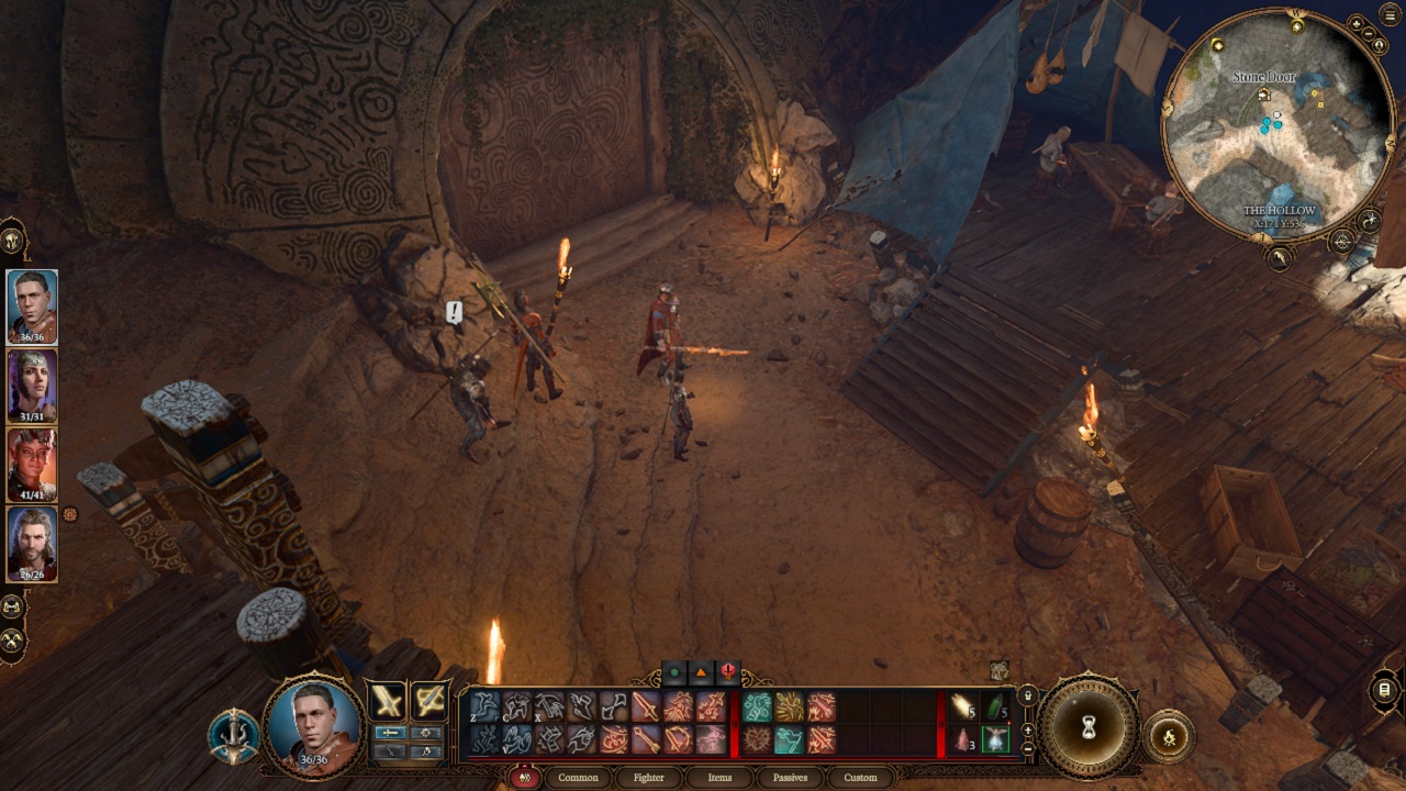 There is a stone door that is closed, with a group of adventurers nearby. There are wooden objects all around, with a staircase that leads to a wooden floor.