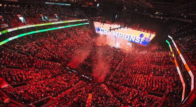 A massive stadium with thousands of fans watching a screen that says "Champions."