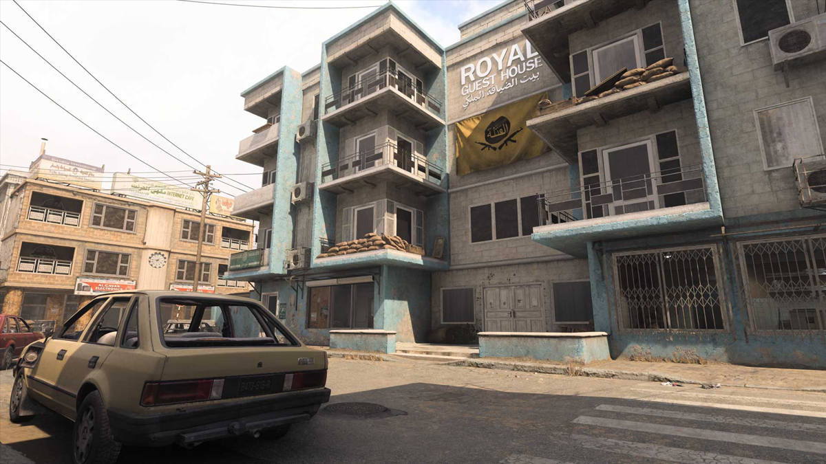 An old yellow car sits in the carpark of a hotel with a green facade in Call of Duty.