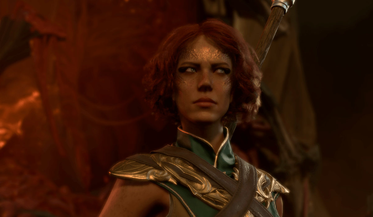 A Wood Half-Elf with short red hair, wearing a green and golden robe looks to the side