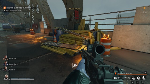 A heister with a weapon points the camera at a cluster of yellow metal beams, with a couple of wheel ramps highlighted on the top of the pile.