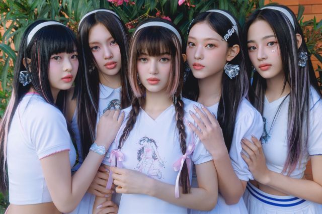 K-pop group NewJeans standing together.