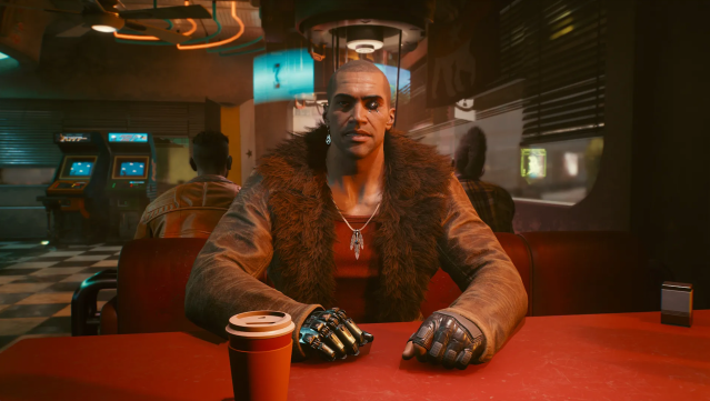 River Ward sits at a red table in a diner in Cyberpunk 2077. 