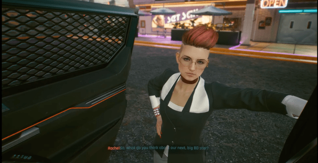 Rachel leans on the side of a car and talks to V in There is a Light That Never Goes Out in Cyberpunk 2077. 