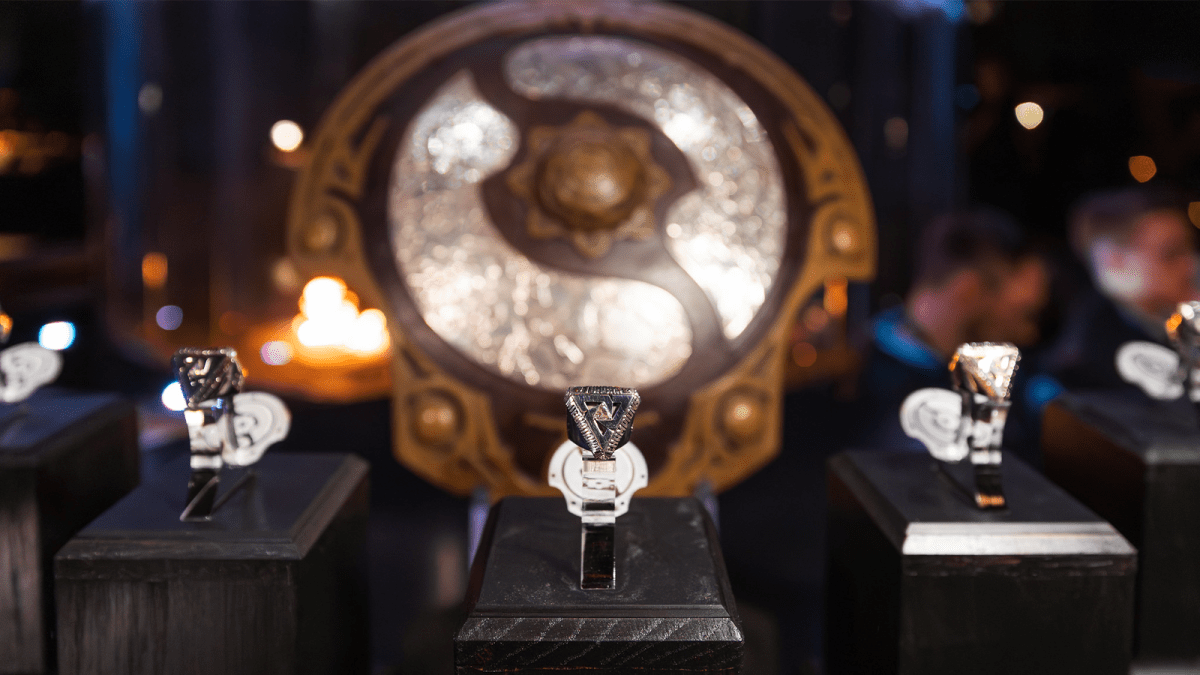 The Dota 2 Aegis of Champions displayed behind Tundra's TI11 rings.