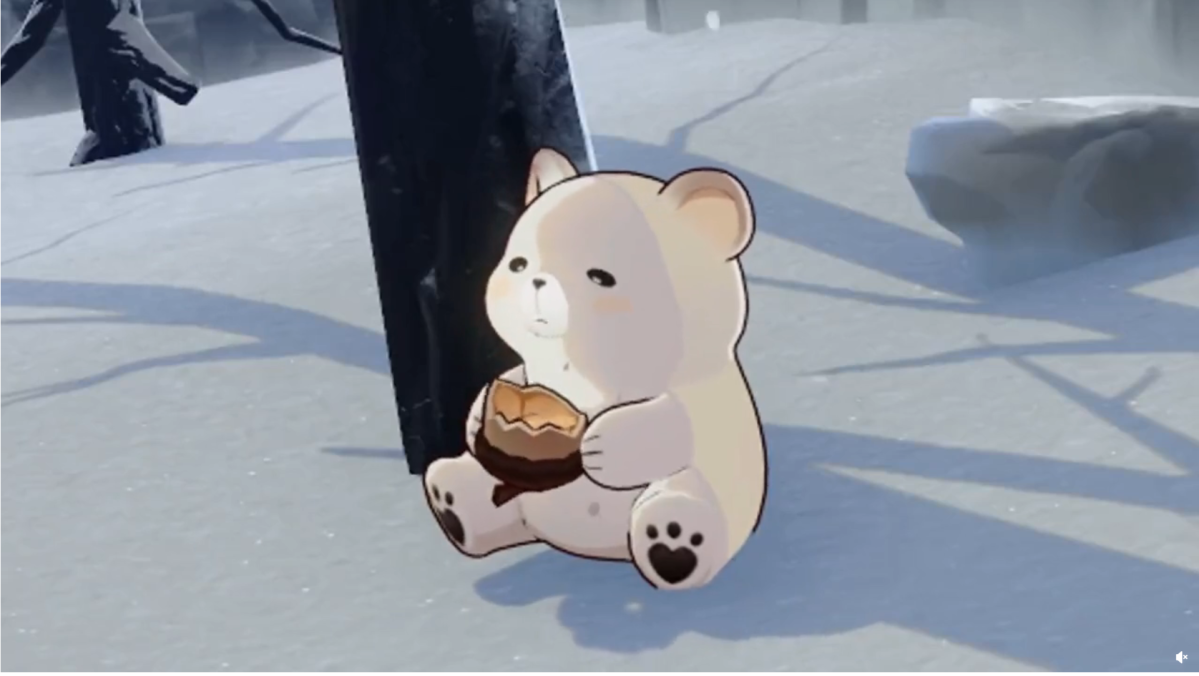 A little bear cub eats an acorn-shaped nut under a tree. The surroundings are covered by snow.