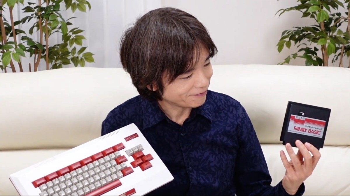 Masahiro Sakurai, from one of his live streams, holding a keyboard and a game.