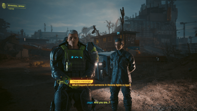 Jago and his bodyguard standing in a parking lot at night (Cyberpunk 2077).