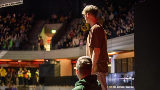 Mande stands on his desk and stares out at the crowd during an ALGS LAN.