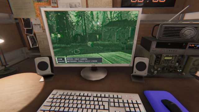 A computer screen on a desk looking at a green camera view on the Camp Woodwind map looking at the campfire area in Phasmophobia.