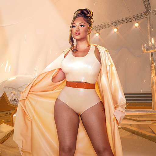 An image from Fortnite Festival of the Big Energy cover art. This features Latto standing in a tan outfit. 