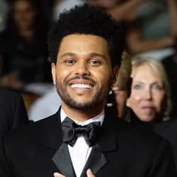 An image from Fortnite Festival of the Popular cover art, which is a photo of the Weeknd smiling on a red carpet. 