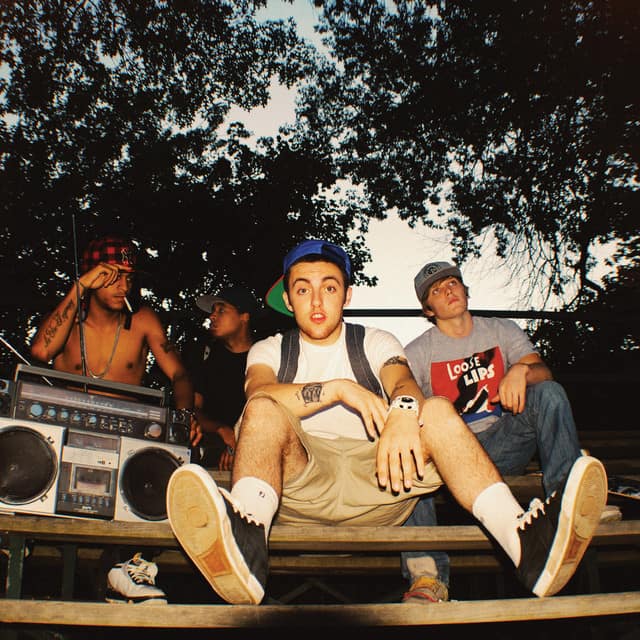 An image from Fortnite Festival of the Spins cover art. This features Mac Miller sitting on a bench. 