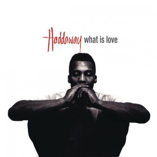 An image of the cover art to What Is Love, which features a man sitting against a white backgroud. This is a song in Fortnite Festival.