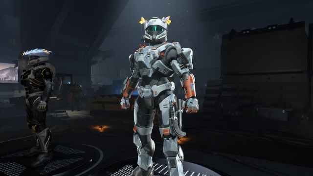 A Spartan standing in the armory hall with the Winterslash Flame armor coating equipped. The coating is light gray and rust orange, with a geometric camo pattern.