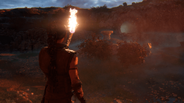 Senua looks at a brazier standing among blue, glimmering light