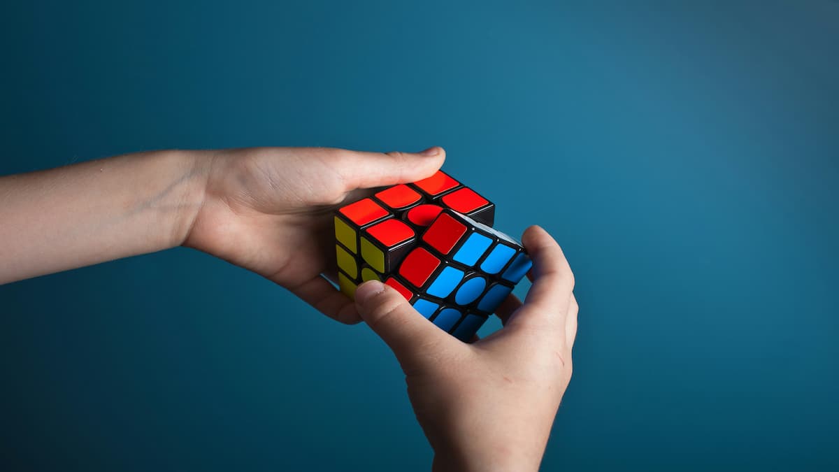 A pair of hands holding and solving a Rubik's Cube.