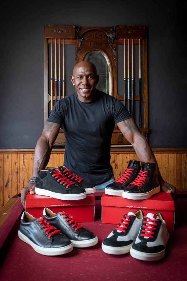 Several shoes with red laces on a red box and pool table, with pool sticks hanging in the background.