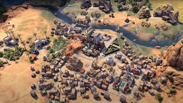 An image of a growing cityscape in Civilization 7. This town is founded next to a river and has multiple stone buildings.