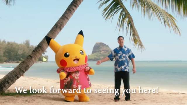 Man standing next to Pikachu on a Hawaiian beach.