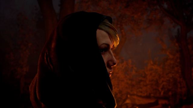 Side profile shot of Augustine Lieber wearing a hood, in front of a lit campfire