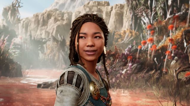 A young woman in Nordic clothing with elaborate braids smiles at something off-screen. Image of Angrboda from God of War Ragnarok