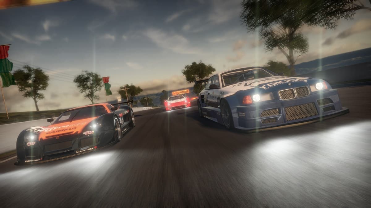 Three cars racing through the street during the evening with trees in the background