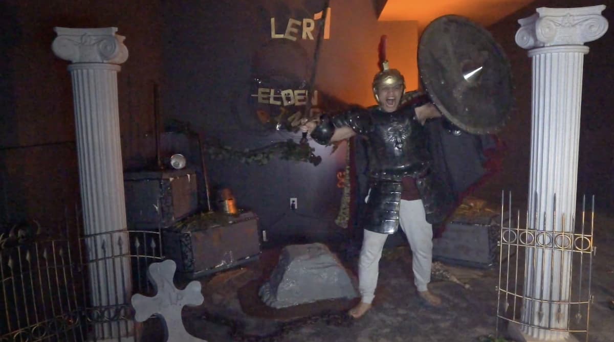 Tyler1 entering his streaming room in a cosplay outfit, looking like a warrior with a shield and sword.