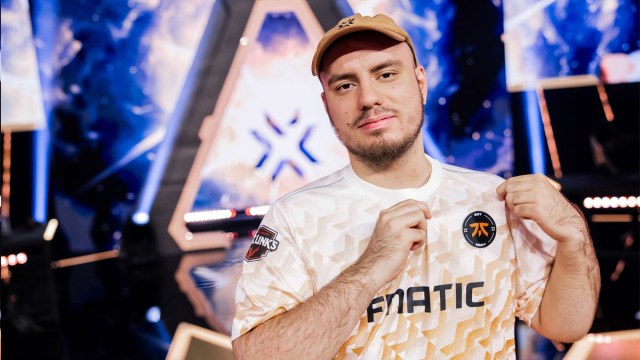 Fnatic player Derke points to his jersey logo while standing on-stage after a win at VCT Champions.