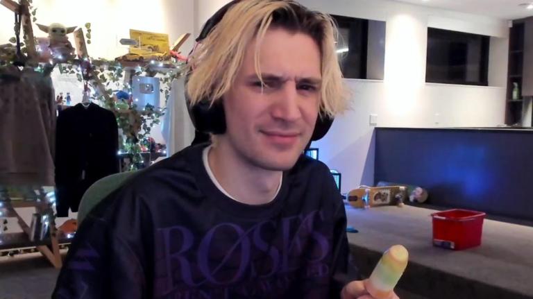 XQc looks confused while eating an icey pole in the middle of his slightly cluttered streaming room