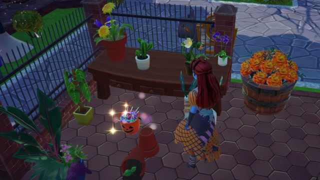 An Orange Candy Bucket on the ground by a table, some plants, and a fallen over pot in Disney Dreamlight Valley.