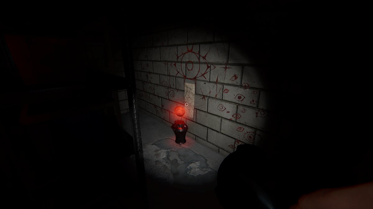 A Totem sitting on the ground behind some metal shelves in the first basement room at 13 Willow Street in Phasmophobia. 