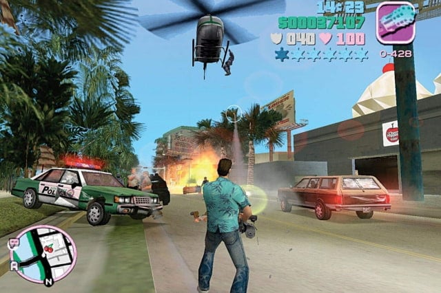 GTA Vice City screenshot of Tommy Vercetti with a minigun firing on several cars while a helicopter flies overhead.