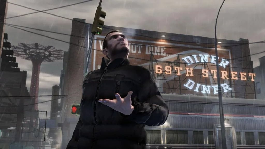 GTA 4 screenshot with Niko in the rain. A neon diner sign and skyscrapers rise in the background.