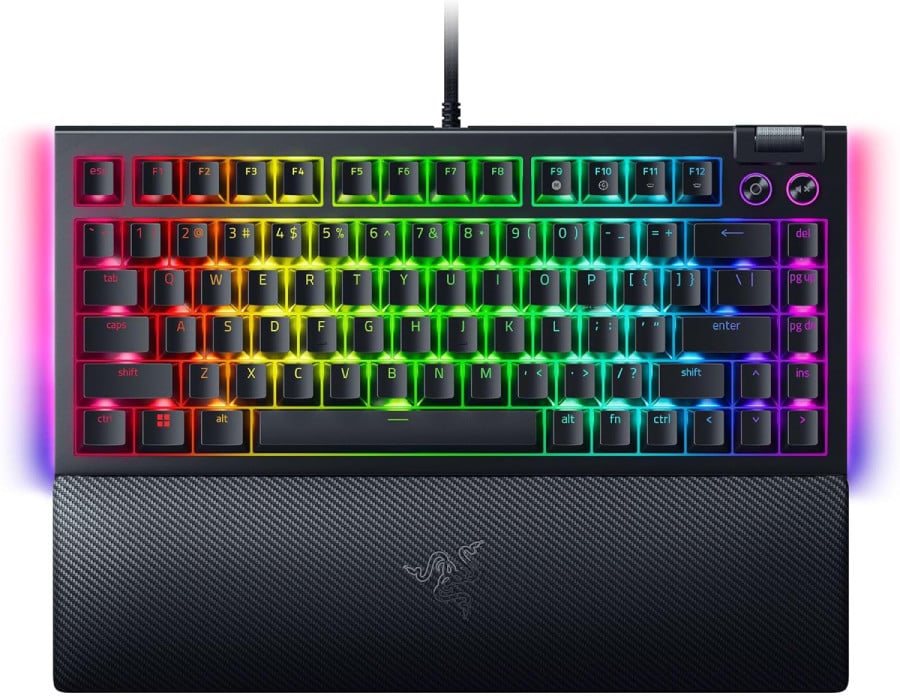 Top-down view of the Razer BlackWidow V4 75% with RGB lights fully illuminated. It has the entire function key row, two steel buttons for power and audio toggling, and a textured wrist rest with the Razer logo. More details below.