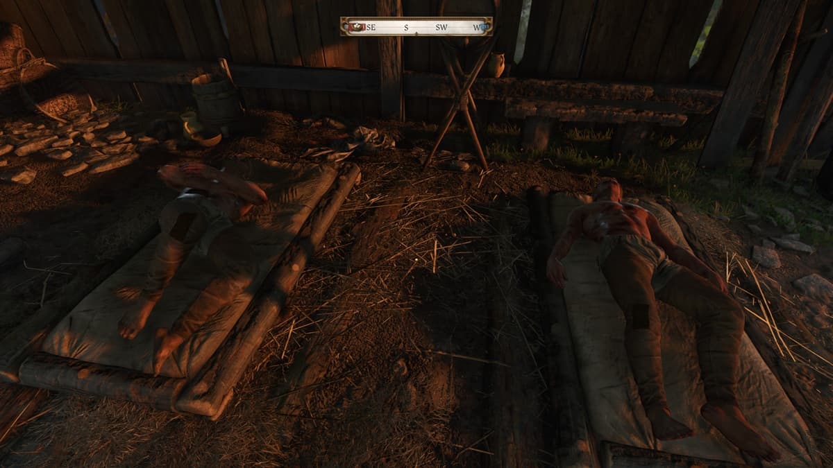 Two wounded men lying on straw beds in a makeshift clinic