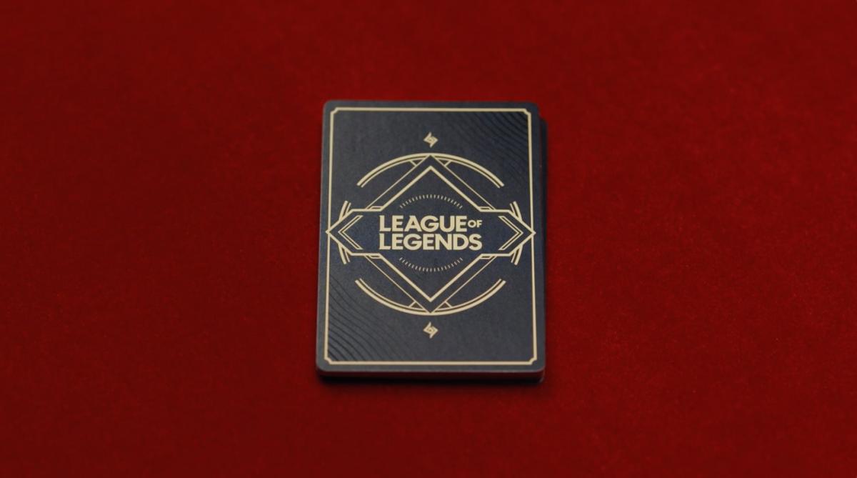 A deck of cards with the League of Legends wordmark on them against a red background
